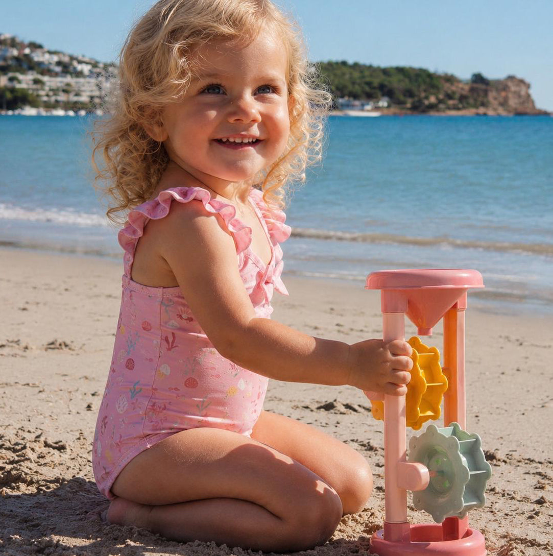 Mädchen spielt am Strand mit Sandspielzeug und Badezubehör